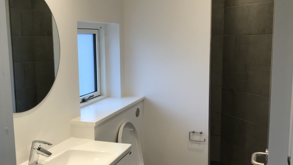 Lyst, nyt badeværelse med grå klinker i brusekabine